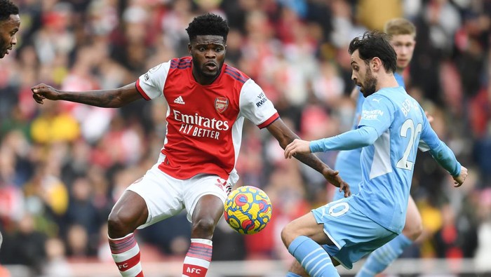 LONDON, ENGLAND - JANUARY 01: Thomas Partey of Arsenal challenges Bernardo Silva of Man City during the Premier League match between Arsenal  and  Manchester City at Emirates Stadium on January 01, 2022 in London, England. (Photo by Stuart MacFarlane/Arsenal FC via Getty Images)