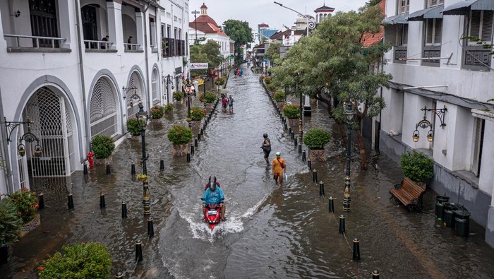 BANJIR DI KAWASAN CAGAR BUDAYA NASIONAL KOTA LAMA SEMARANG Warga mendorong sepeda motornya yang mogok di jalan yang terendam banjir di Kawasan Cagar Budaya Nasional Kota Lama Semarang, Jawa Tengah, Sabtu (31/12/2021). Sejumlah jalan di kawasan cagar budaya nasional dengan julukan