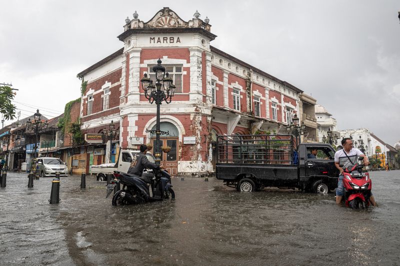 BANJIR DI KAWASAN CAGAR BUDAYA NASIONAL KOTA LAMA SEMARANG Warga mendorong sepeda motornya yang mogok di jalan yang terendam banjir di Kawasan Cagar Budaya Nasional Kota Lama Semarang, Jawa Tengah, Sabtu (31/12/2021). Sejumlah jalan di kawasan cagar budaya nasional dengan julukan