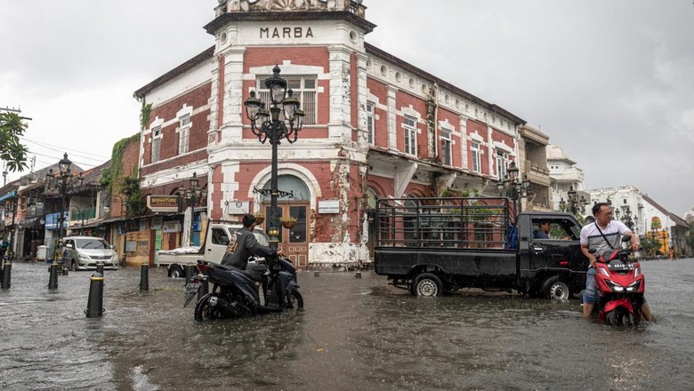 BANJIR DI KAWASAN CAGAR BUDAYA NASIONAL KOTA LAMA SEMARANG Warga mendorong sepeda motornya yang mogok di jalan yang terendam banjir di Kawasan Cagar Budaya Nasional Kota Lama Semarang, Jawa Tengah, Sabtu (31/12/2021). Sejumlah jalan di kawasan cagar budaya nasional dengan julukan