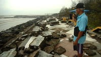 Seorang warga melihat kondisi tembok jogging track yang hancur di pinggir Pantai Alam Indah, Tegal, Jawa Tengah, Sabtu (31/12/2022). 