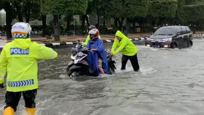 Petugas membatu pengendara motor melewati genangan di Jalan Simpang Lima Semarang, Sabtu (31/12/2022).