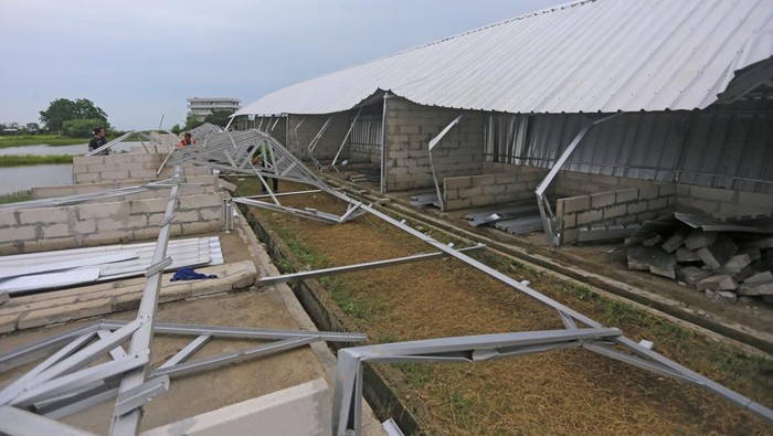 Pekerja merapikan atap bangunan pasar yang ambruk di Juntinyuat, Indramayu, Jawa Barat, Senin (1/1/2023). Bangunan pasar yang baru selesai dibangun itu ambruk setelah diterpa angin kencang. ANTARA FOTO/Dedhez Anggara/rwa.