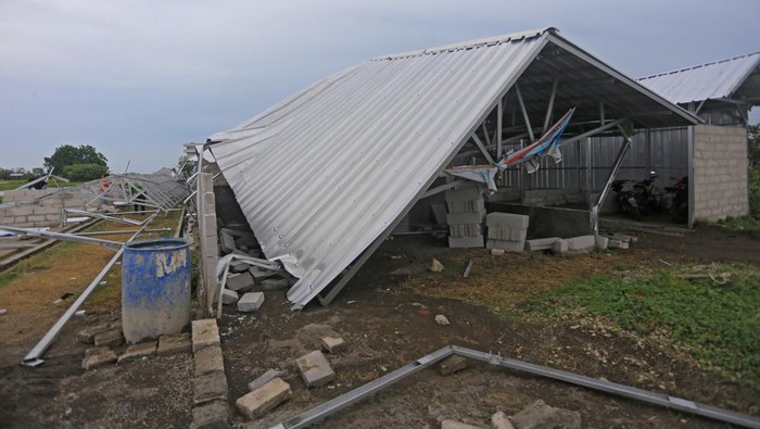 Pekerja merapikan atap bangunan pasar yang ambruk di Juntinyuat, Indramayu, Jawa Barat, Senin (1/1/2023). Bangunan pasar yang baru selesai dibangun itu ambruk setelah diterpa angin kencang. ANTARA FOTO/Dedhez Anggara/rwa.