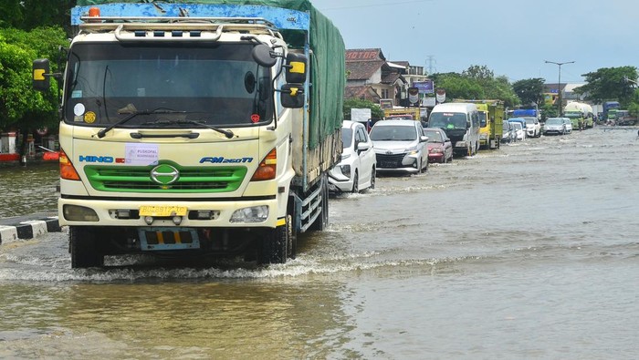 Sejumlah kendaraan menerobos jalan yang tergenang banjir di jalan Jalur Pantura Desa Jati Wetan, Kudus, Jawa Tengah, Minggu (1/1/2023). Banjir akibat curah hujan tinggi itu menyebabkan kemacetan dari arah Kudus menuju Semarang dan sebaliknya. ANTARA FOTO/Yusuf Nugroho/rwa.
