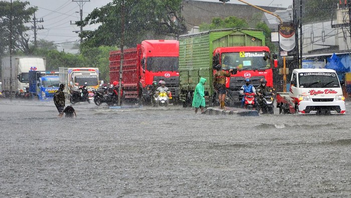 Sejumlah kendaraan menerobos jalan yang tergenang banjir di jalan Jalur Pantura Desa Jati Wetan, Kudus, Jawa Tengah, Minggu (1/1/2023). Banjir akibat curah hujan tinggi itu menyebabkan kemacetan dari arah Kudus menuju Semarang dan sebaliknya. ANTARA FOTO/Yusuf Nugroho/rwa.