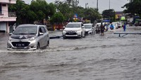 Sejumlah kendaraan menerobos jalan yang tergenang banjir di jalan Jalur Pantura Desa Jati Wetan, Kudus, Jawa Tengah, Minggu (1/1/2023).