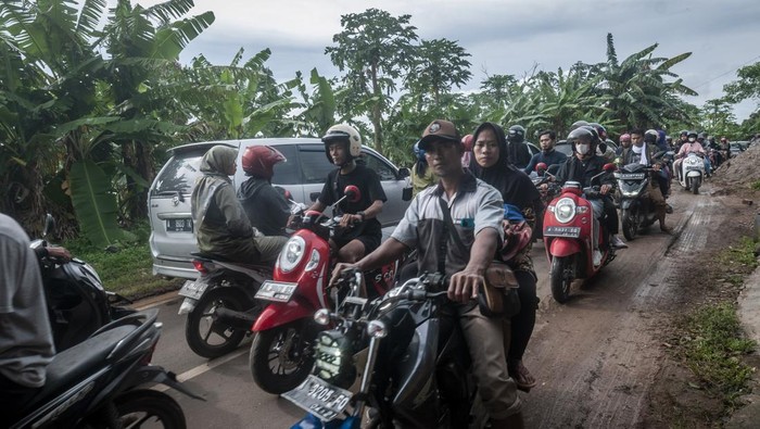 Sejumlah pengunjung menumpang kendaraan bak terbuka saat terjebak kemacetan di jalur Mancak-Anyer di Kabupaten Serang, Banten, Minggu (1/1/2023). Pada libur Tahun Baru 2023, arus lalu lintas menuju kawasan wisata Pantai Anyer, Carita, dan Kawasan Ekonomi Khusus (KEK) Tanjung Lesung terpantau padat antrean sekitar lebih dari dua kilometer. ANTARA FOTO/Muhammad Bagus Khoirunas/rwa.