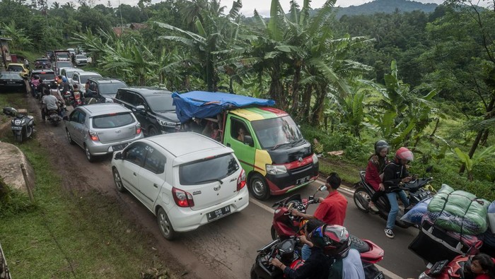 Sejumlah pengunjung menumpang kendaraan bak terbuka saat terjebak kemacetan di jalur Mancak-Anyer di Kabupaten Serang, Banten, Minggu (1/1/2023). Pada libur Tahun Baru 2023, arus lalu lintas menuju kawasan wisata Pantai Anyer, Carita, dan Kawasan Ekonomi Khusus (KEK) Tanjung Lesung terpantau padat antrean sekitar lebih dari dua kilometer. ANTARA FOTO/Muhammad Bagus Khoirunas/rwa.