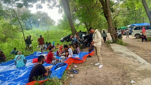 Warga Labuan Bajo duduk lesehan di bawah pohon di pinggir Pantai Pede, Minggu siang (1/1/2023). (Ambrosius Ardin)