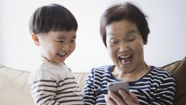 An asian senior woman and her grand son using a smartphone together.