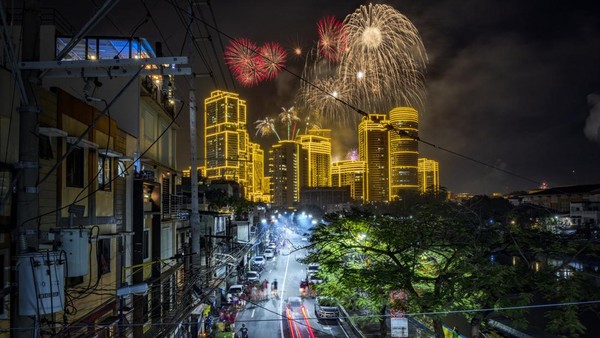 Kembang api menyala di atas gedung pencakar langit selama perayaan tahun baru, di Makati, Manila, Filipina, Minggu (1/1/2023).    