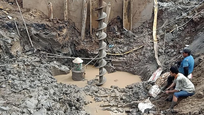 Rescuers gather at the site of where a 10-year-old boy is thought to be trapped in a 35-metre deep shaft at a bridge construction area in Vietnams Dong Thap province on January 2, 2023. - Hundreds of rescuers in Vietnam battled January 2 to free a 10-year-old boy who fell into a 35-metre deep hole on a construction site two days ago. (Photo by AFP)
