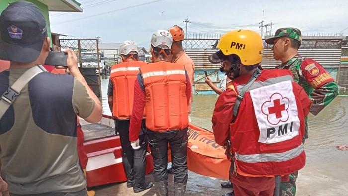 Petugas mengevakuasi korban tewas akibat tersengat listrik di lokasi banjir, Genuk, Semarang, Senin (2/1/2022).