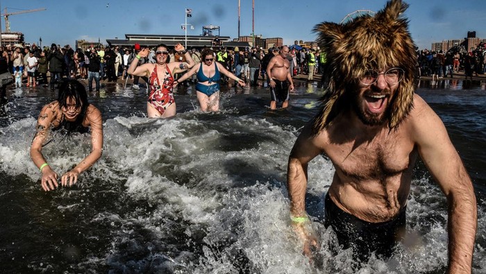 Sambut Tahun Baru, Warga AS Ramai-ramai Berenang di Samudra Atlantik People run into the Atlantic Ocean during the annual Coney Island Polar Bear Club New Year's Day Plunge in Brooklyn, New York, U.S., January 1, 2023. REUTERS/Stephanie Keith