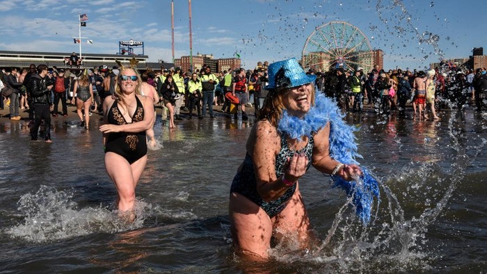 Sambut Tahun Baru, Warga AS Ramai-ramai Berenang di Samudra Atlantik People run into the Atlantic Ocean during the annual Coney Island Polar Bear Club New Year's Day Plunge in Brooklyn, New York, U.S., January 1, 2023. REUTERS/Stephanie Keith