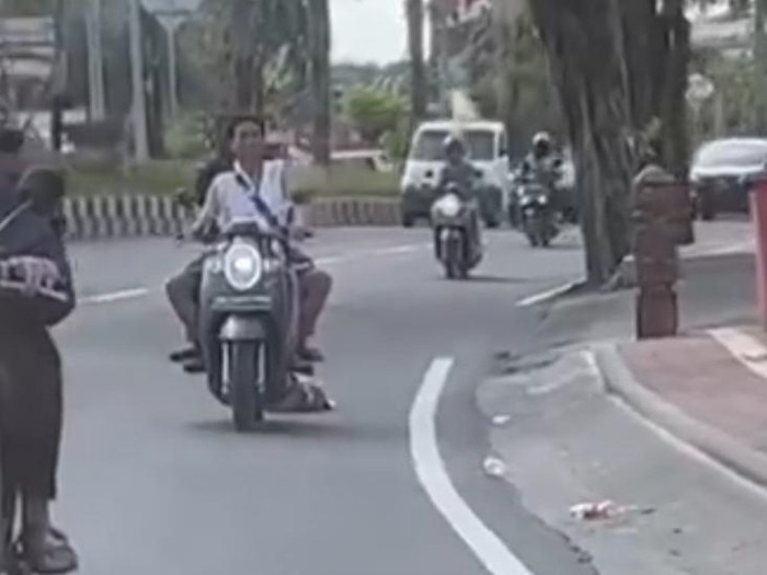 Tangkapan layar video viral pemotor berboncengan menyeret bangkai anjing dan dibuang ke sungai. (I Wayan Sui Suadnyana/detikBali)