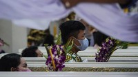 Warga tampak memegang bunga saat mengikuti upacara pemakaman tradisional itu.