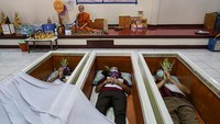 Sejumlah warga tidur di dalam peti mati saat mengikuti sebuah upacara di Kuil Wat Bang Na Nai, Bangkok, Thailand, Minggu (1/1/2023).  