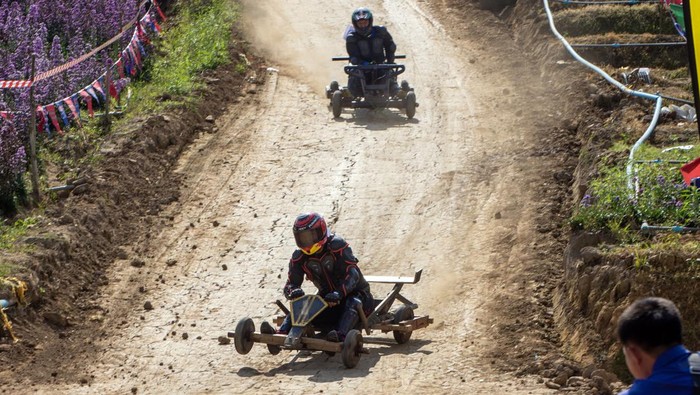 CHIANG MAI, THAILAND - 2022/12/26: Hmong hill tribe men race wooden carts (known as Formula Hmong) during traditional Hmong New Year celebrations. In December or January, the Hmong celebrate their new year, called Noj Peb Caug (pronounced Nor Pe Chao). A larger public celebration takes place at an outdoor venue, There are many activities during this event, such as top-spinning games, arrow shooting contests, singing and dancing, and courtship games. Young men and women wear colorful interpretations of traditional clothing, in the hopes of attracting a life partner. Visitors are welcome to attend and can partake in photo booths with traditional clothes, play games, and watch local performances. Nowadays, traditional clothing is worn only on special occasions like wedding ceremonies and the New Year. (Photo by Pongmanat Tasiri/SOPA Images/LightRocket via Getty Images)