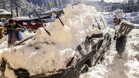 Dua orang warga mencoba untuk membersihkan mobilnya dari tumpukan salju di Tahoe Lakeshore Lodge & Spa. AP/Stephen Lam  