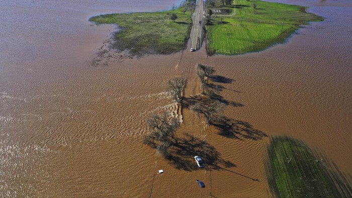 Three vehicles are submerged on Dillard Road west of Highway 99 in south Sacramento County in Wilton, Calif., Sunday, Jan. 1, 2023, after heavy rains on New Year's Eve produced levee breaks. Saturday's system was warmer and wetter, while storms this week will be colder, said Hannah Chandler-Cooley, a meteorologist at the National Weather Service in Sacramento. The Sacramento region could receive a total of 4 to 5 inches (10 to 13 centimeters) of rain over the week, Chandler-Cooley said. (Hector Amezcua/The Sacramento Bee via AP)