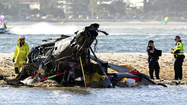 Two cashed helicopters sit on the sand at a collision scene near Seaworld, on the Gold Coast, Australia, Monday, Jan. 2, 2023. The 2 helicopters collided killing several passengers and critically injuring a few others in a crash that drew emergency aid from beachgoers enjoying the water during the southern summer. (Dave Hunt/AAP Image via AP)