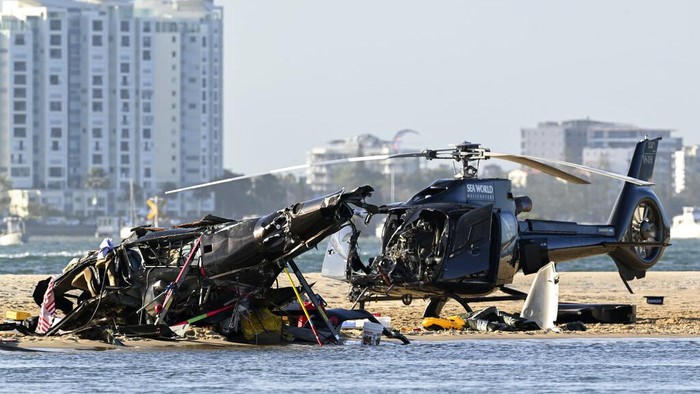 Two cashed helicopters sit on the sand at a collision scene near Seaworld, on the Gold Coast, Australia, Monday, Jan. 2, 2023. The 2 helicopters collided killing several passengers and critically injuring a few others in a crash that drew emergency aid from beachgoers enjoying the water during the southern summer. (Dave Hunt/AAP Image via AP)