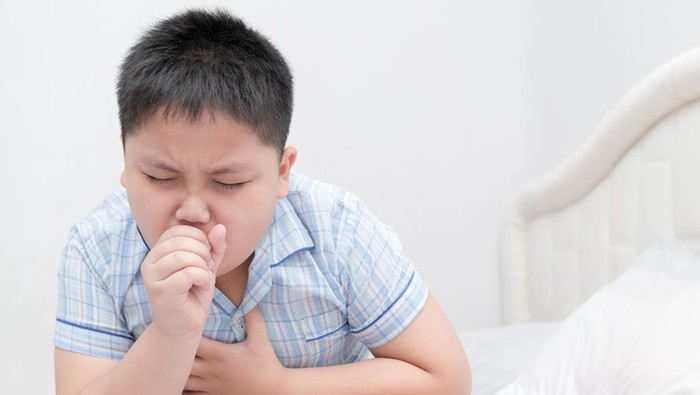 Sick obese boy is coughing and throat infection on bed, health care concept