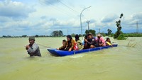 Sebagian warga memilih untuk menggunakan perahu saat melintasi jalan yang tergenang banjir.  Intensitas hujan yang tinggi sejak Jumat 30/12/2022 menyebabkan akses jalan utama sepanjang satu kilometer di desa tersebut terendam banjir.  