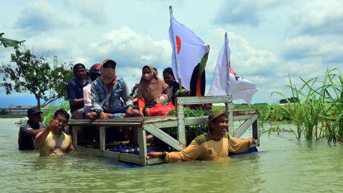 Jalan Utama Desa di Kudus Terendam Banjir Akibat Hujan Deras Warga menggunakan perahu rakit melintasi jalan yang tergenang banjir di Karangturi, Setrokalangan, Kudus, Jawa Tengah, Selasa (3/1/2023). Intensitas hujan yang tinggi sejak Jumat 30/12/2022 menyebabkan akses jalan utama sepanjang satu kilometer di desa tersebut terendam banjir dengan ketinggian hingga satu meter dan sebanyak kurang lebih 1.500 jiwa terisolasi. ANTARA FOTO/Yusuf Nugroho/foc.