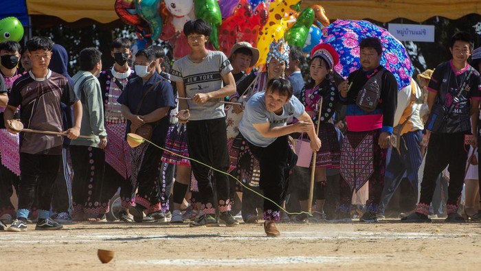 Melihat Serunya Adu Gasing Kayu Khas Thailand CHIANG MAI, THAILAND - 2022/12/26: Hmong hill tribe men playing top spinning competition (traditional game of tujlub which involves spinning wooden tops hurled with string and sticks. While one top is still spinning, another person tries to hit it. If they don't hit it, they're out. If they do hit it, the winner is the one whose top continues spinning the longest.) during the Hmong New Year celebrations. In December or January, the Hmong celebrate their new year, called Noj Peb Caug (pronounced Nor Pe Chao). A larger public celebration takes place at an outdoor venue, There are many activities during this event, such as top-spinning games, arrow shooting contests, singing and dancing, and courtship games. Young men and women wear colorful interpretations of traditional clothing, in the hopes of attracting a life partner. Visitors are welcome to attend and can partake in photo booths with traditional clothes, play games, and watch local performances. Nowadays, traditional clothing is worn only on special occasions like wedding ceremonies and the New Year. (Photo by Pongmanat Tasiri/SOPA Images/LightRocket via Getty Images)
