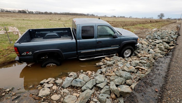 Cars are piled up next to a wheelchair submerged in the water after rainstorms caused flooding in Sacramento County, in Wilton, California, U.S. January 2, 2023. REUTERS/Fred Greaves