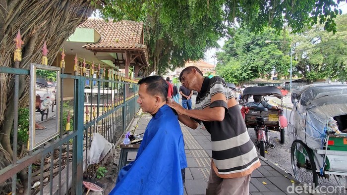 Pangkas rambut di bawah beringin Alun-alun Utara Jogja. Foto diambil Minggu (1/3/2023).