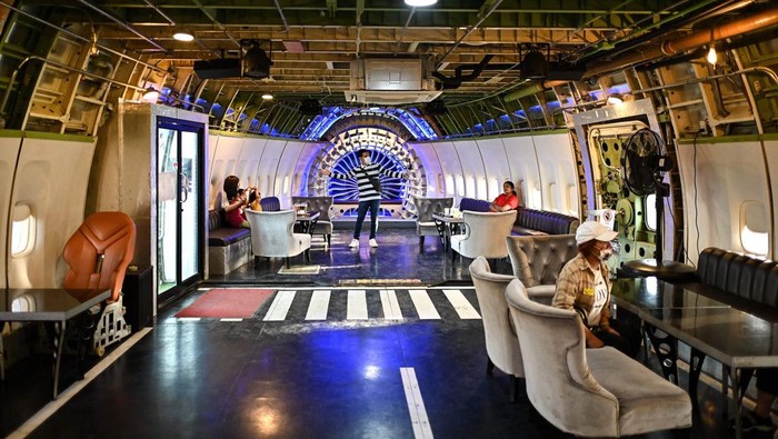 Pesawat Bekas Disulap Jadi Restoran di Thailand A woman rides a swing at the 747 cafe, designed inside a decommissioned Boeing 747-400 airplane on the outskirts of Bangkok on January 2, 2023. (Photo by MANAN VATSYAYANA / AFP) (Photo by MANAN VATSYAYANA/AFP via Getty Images)