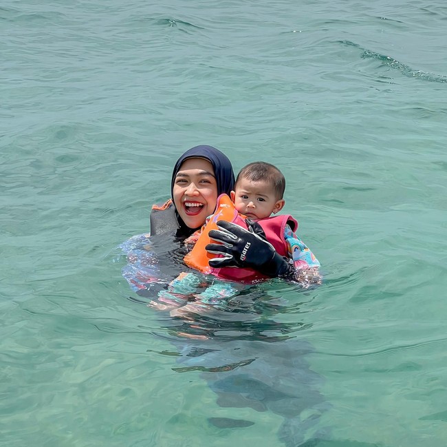 Melalui akun Instagram dan YouTube miliknya, Ria Ricis membagikan momen-momen keseruannya bersama suami, anak, dan para timnya saat berada di Bali. Ricis dan Ryan untuk pertama kalinya juga mengajak sang anak untuk berenang di laut. Foto: Instagram/@riaricis1795