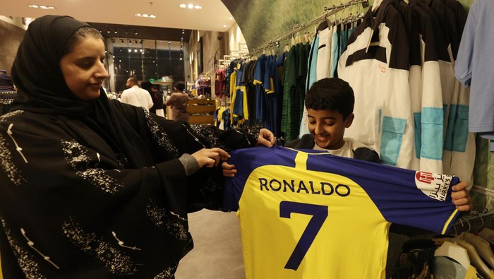 Soccer Football - Al Nassrs Cristiano Ronaldo arrives in Saudi Arabia - Riyadh, Saudi Arabia - January 2, 2023 A fan holds up a Al Nassr jersey with Cristiano Ronaldos name and number on the back in the Al Nassr club shop REUTERS/Ahmed Yosri