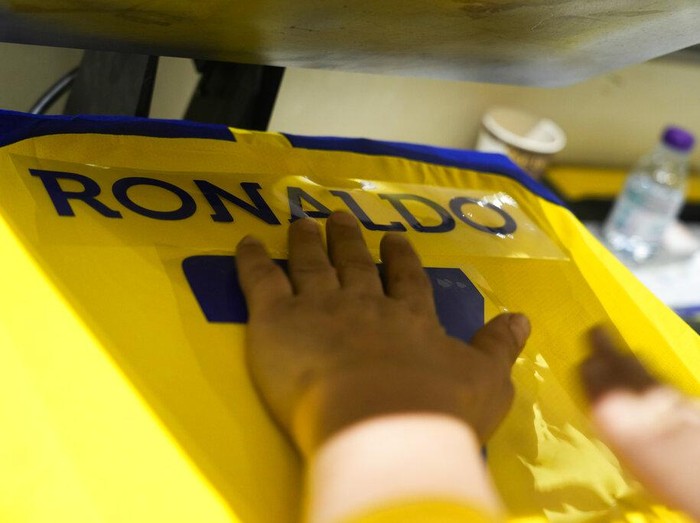 An employee prints out Cristiano Ronaldo jerseys at Al Nassr soccer club store in Riyadh, Saudi Arabia, Monday, Jan 2, 2023. Ronaldo completed a lucrative move to Saudi Arabian club Al Nassr on Friday in a deal that is a landmark moment for Middle Eastern soccer but will see one of Europe's biggest stars disappear from the sport's elite stage. (AP Photo/Amr Nabil)