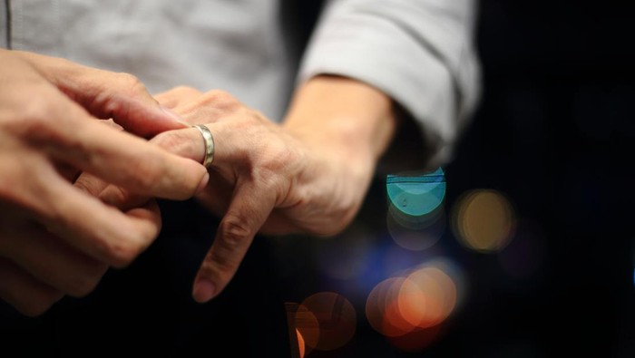 man putting on wedding ring. close up shot of man fidgeting ring with nice out of focus urban light backgrounds.
