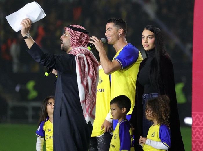 Gaya Georgina Rodriguez di Arab Saudi Al-Nassrs new Portuguese forward Cristiano Ronaldo (C), his partner Georgina Rodriguez (2nd-L) and his children stand on the stage during his unveiling at the Mrsool Park Stadium in the Saudi capital Riyadh on January 3, 2023. (Photo by Fayez Nureldine / AFP) (Photo by FAYEZ NURELDINE/AFP via Getty Images)