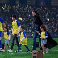 Walau serba polos, gaya Georgina Rodríguez jauh dari kesan monoton berkat anting berlian yang menghiasi telinganya. Jari manis kanannya juga dilingkari sebuah cincin berlian yang disebut-sebut sebagai bukti pertunangannya dengan Ronaldo. (Foto: Getty Images/Yasser Bakhsh)