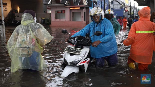 Warga menerobos banjir menggunakan sepeda motor di kawasan Seskol, Jakarta, Rabu (4/1/2023). Hujan deras mengguyur sejumlah wilayah di DKI Jakarta. (CNBC Indonesia/Tri Susilo)
