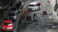 Jalan yang berlubang membuat para pengendara melambatkan kecepatannya hingga harus berkendara zigzag demi menghindari lubang. 