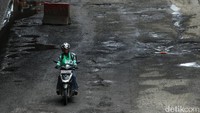 Terlihat ada pengendara sepeda motor yang telanjur mengambil lajur kiri dan terperangkap di kerusakan jalan. 