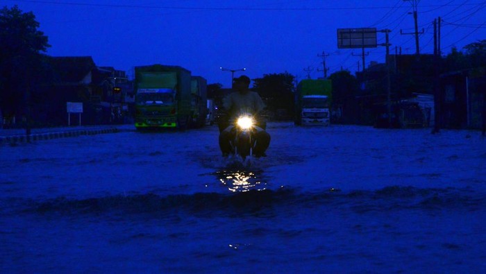 Sejumlah kendaraan menerobos jalan yang tergenang banjir di jalan nasional jalur Pantura (Pantai Utara) Desa Jati Wetan, Kudus, Jawa Tengah, Selasa (3/1/2023). Banjir akibat curah hujan tinggi tersebut menyebabkan kemacetan dari arah Kudus menuju Semarang dan sebaliknya sejak Minggu 1/1/2023.