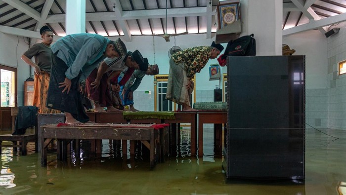 Sejumlah warga melaksankan Shalat Asar berjamaah di atas meja yang diletakkan di lantai Masjid Jami Al Muttaqin yang terendam banjir di Desa Prampelan, Kecamatan Sayung, Kabupaten Demak, Jawa Tengah, Selasa, (3/1/2023). Warga setempat memanfaatkan meja untuk saf shalat berkapasitas terbatas karena banjir merendam lantai masjid tersebut dengan ketinggian bervariasi antara 10-30 cm akibat intensitas hujan tinggi sejak Sabtu (31/12/2022) dini hari. ANTARA FOTO/Aji Styawan/foc.