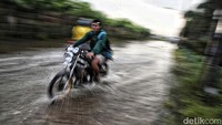 Seorang pengendara sepeda motor menerobos genangan di Jalan Raya Tarumajaya-Marunda.