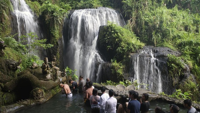 OBJEK WISATA RELIGI DI BALI Wisatawan mengikuti ritual melukat atau pembersihan diri di Taman Beji Griya Waterfall, Desa Punggul, Badung, Bali, Kamis (5/1/2023). Ritual melukat di objek wisata religi tersebut untuk membersihkan diri dan pikiran secara spiritual dari hal-hal negatif. ANTARA FOTO/Nyoman Hendra Wibowo/rwa.