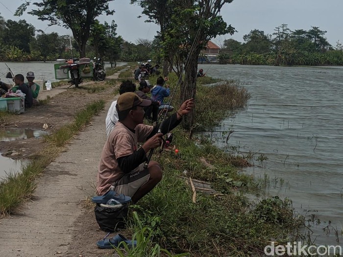 Warga memancing di sawah yang terendam banjir di Desa Prampelan, Kecamatan Sayung, Demak, Jawa Tengah, Kamis (5/1/2023).