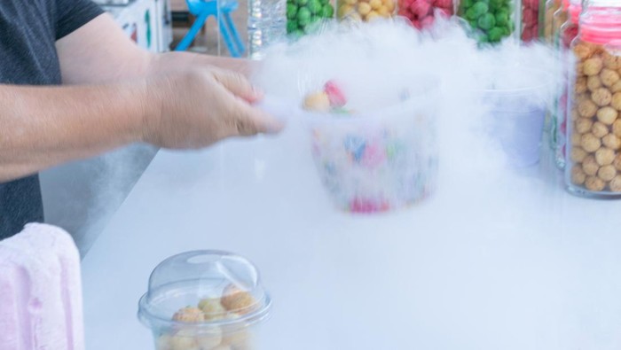 Sweet colored candies with steam of nitrogen liquid in a cup in a market